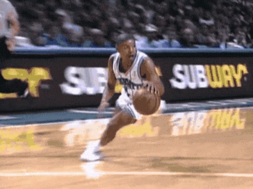 A Basketball Player Is Dribbling The Ball In Front Of A Subway Ad GIF