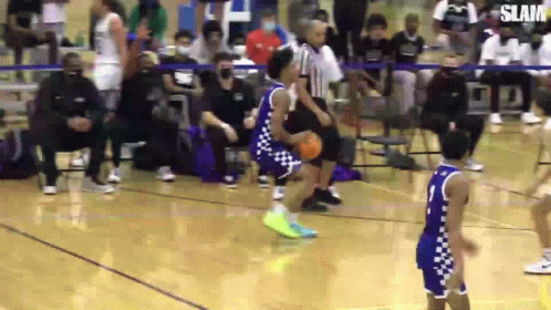 A Basketball Player Is Dribbling The Ball On A Court While Another Player Tries To Block Him . GIF