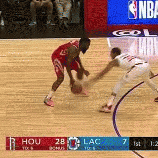 A Basketball Player Is Dribbling The Ball While Another Player Tries To Block Him . GIF