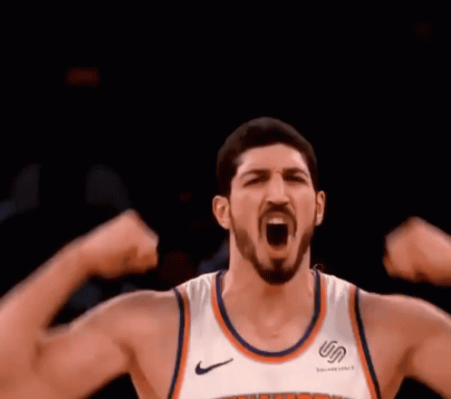 A Basketball Player Is Flexing His Muscles While Wearing A New York Knicks Jersey . GIF