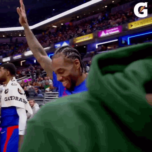 A Basketball Player Is Giving A High Five To The Crowd While Wearing A Green Gatorade Shirt . GIF