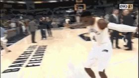 A Basketball Player Is Jumping In The Air While Holding A Basketball In Front Of A Banner That Says Bankers Hill Fieldho GIF