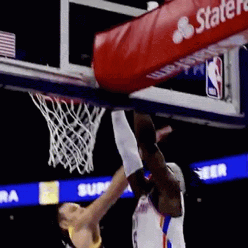 A Basketball Player Is Jumping Over Another Player Who Is Trying To Dunk The Ball . GIF