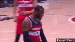 A Basketball Player Is Kneeling Down On The Court While Another Player Stands Behind Him GIF
