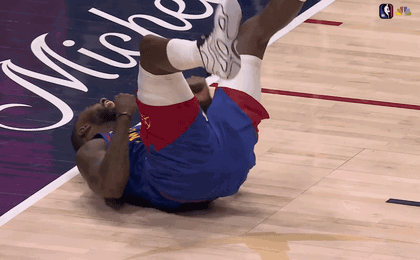 a basketball player is laying on his back on a court with michigan written on it