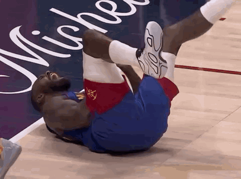 a basketball player is laying on his back on the court