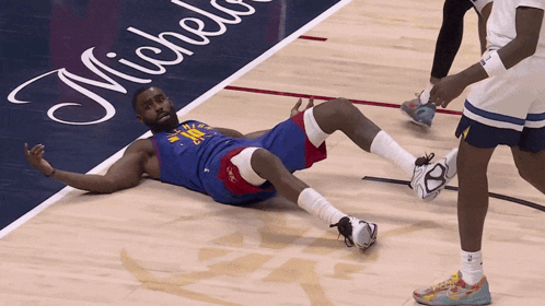 a basketball player is laying on the floor in front of a michelin advertisement