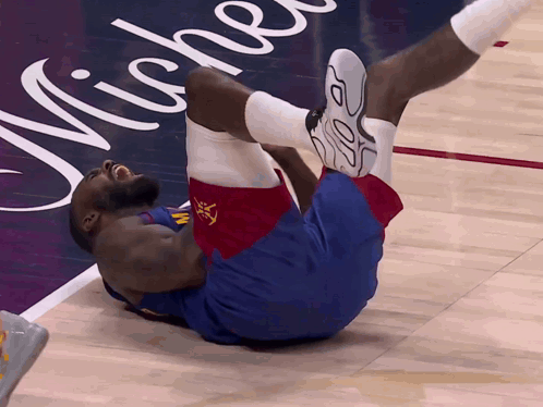 a basketball player is laying on the floor in front of a michelle advertisement