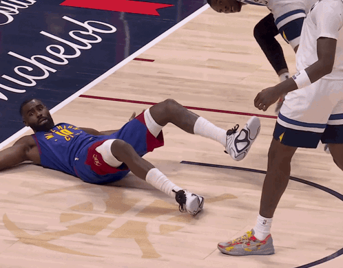 a basketball player is laying on the floor with a michelab sign in the background