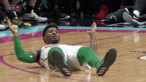 A Basketball Player Is Laying On The Floor With His Legs Crossed . GIF