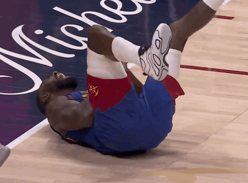 a basketball player is laying on the floor with his legs up