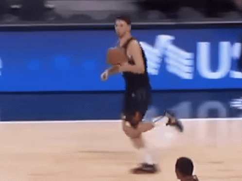 A Basketball Player Is Running On The Court In Front Of A Sign That Says U GIF