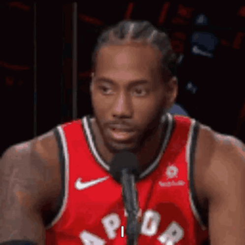 A Basketball Player Is Sitting In Front Of A Microphone . GIF
