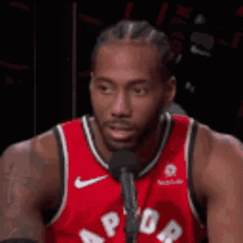 A Basketball Player Is Sitting In Front Of A Microphone . GIF