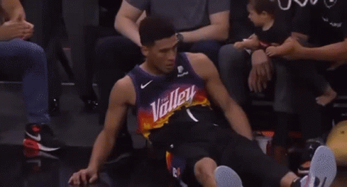 A Basketball Player Is Sitting In The Stands Giving A Thumbs Up To His Fans . GIF