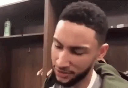 A Basketball Player Is Standing In A Locker Room With His Eyes Closed . GIF