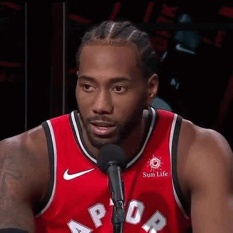 A Basketball Player Is Standing In Front Of A Microphone And Talking Into It . GIF