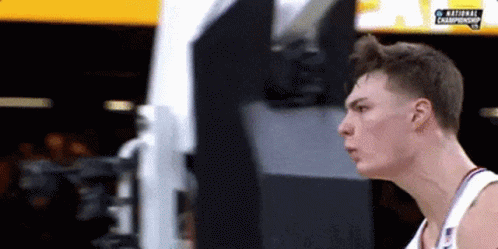 A Basketball Player Is Standing In Front Of A Screen That Says National Championship . GIF