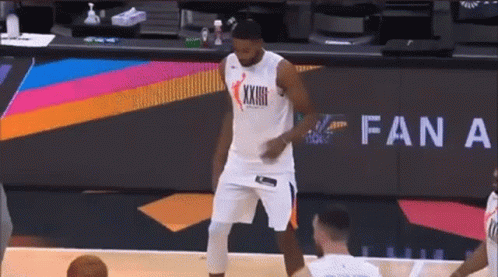 A Basketball Player Is Standing On A Basketball Court In Front Of A Fan A Sign . GIF