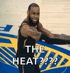A Basketball Player Is Standing On A Court With His Arms Outstretched And Says `` The Heat '' . GIF