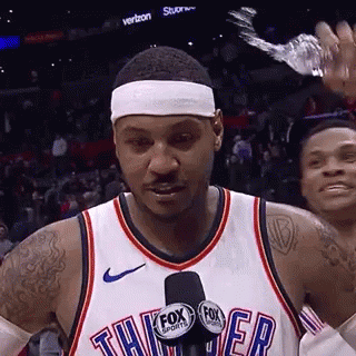 A Basketball Player Is Talking Into A Microphone While Wearing A Headband And Holding A Bottle Of Water . GIF