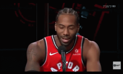 A Basketball Player Is Talking Into A Microphone While Wearing A Red Raptors Jersey . GIF