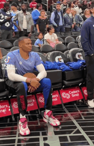 A Basketball Player Sits In The Stands With A Gatorade Advertisement On The Seats GIF