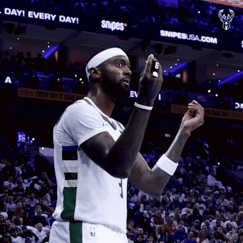 A Basketball Player Stands In Front Of A Sign That Says Snipes On It GIF