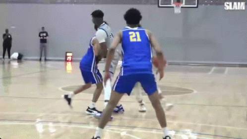 A Basketball Player Wearing A Blue Jersey With The Number 21 On It Is Dribbling The Ball . GIF