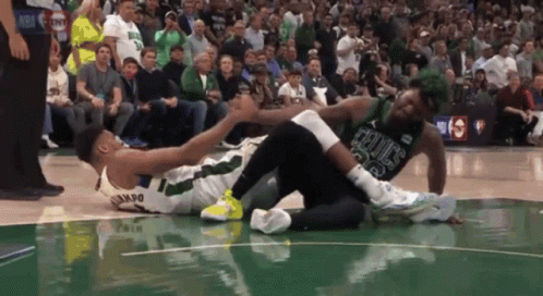 A Basketball Player Wearing A Celtics Jersey Is Laying On The Court GIF