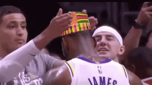a basketball player wearing a crown is being congratulated by his teammates .
