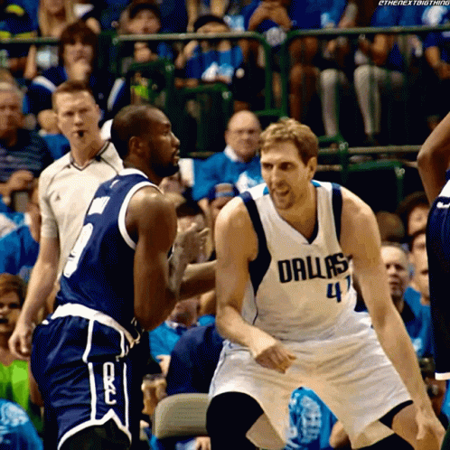 A Basketball Player Wearing A Dallas Jersey Talks To Another Player On The Court GIF