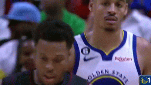 a basketball player wearing a golden state warriors jersey is standing next to another basketball player .