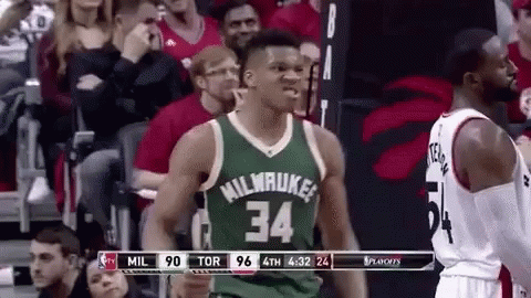 A Basketball Player Wearing A Green Jersey With The Number 34 On It Is Standing In Front Of A Crowd Of People . GIF