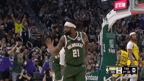 A Basketball Player Wearing A Green Milwaukee Jersey Stands In Front Of A Crowd GIF