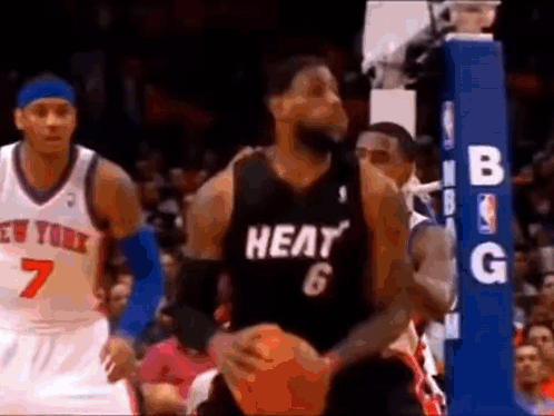 a basketball player wearing a heat jersey is holding a basketball while playing basketball .