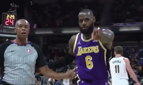 A Basketball Player Wearing A Lakers Jersey Is Pointing At A Referee GIF