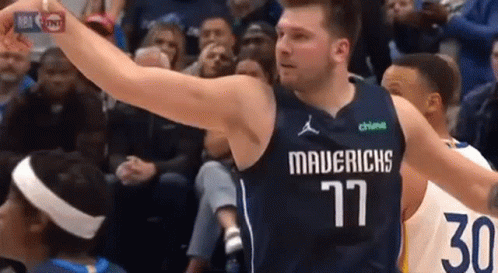 A Basketball Player Wearing A Mavericks Jersey Is Holding A Basketball In His Hand . GIF