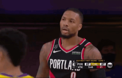 A Basketball Player Wearing A Portland Jersey Stands In Front Of A Referee GIF