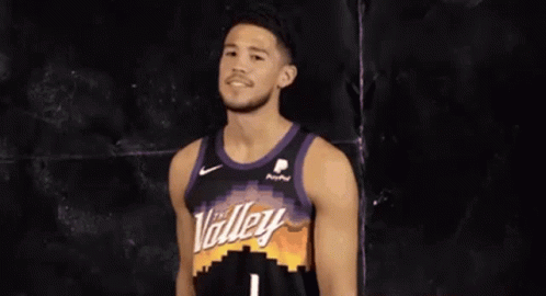 A Basketball Player Wearing A Purple And Black Jersey Is Smiling . GIF