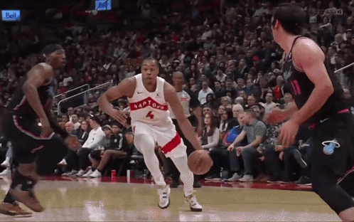a basketball player wearing a raptors jersey dribbles the ball