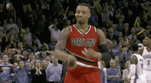 a basketball player wearing a red portland jersey is dancing in front of a crowd