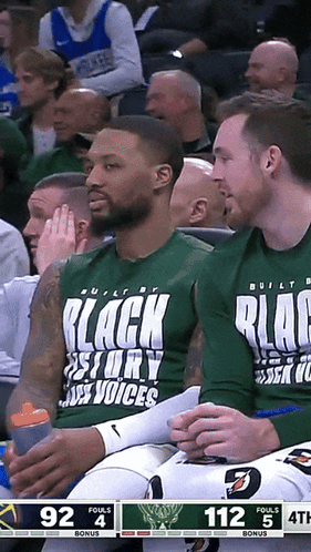 a basketball player wearing a shirt that says black story voices sits in the stands