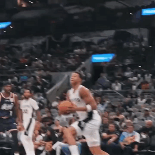 A Basketball Player Wearing A Spurs Jersey Is Jumping To Dunk The Ball GIF