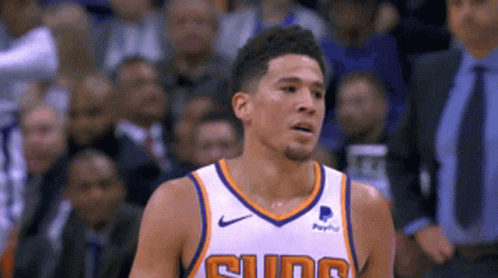 A Basketball Player Wearing A Suns Jersey Looks To The Side GIF