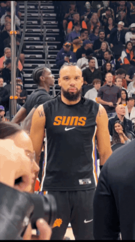 A Basketball Player Wearing A Suns Jersey Stands In Front Of A Crowd GIF