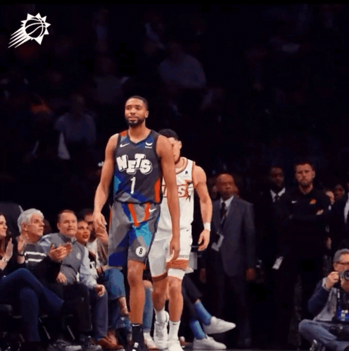 A Basketball Player Wearing A Suns Jersey Talks To Another Player GIF