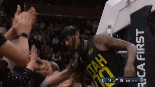 A Basketball Player Wearing A Utah Jersey Is Being Greeted By A Crowd GIF
