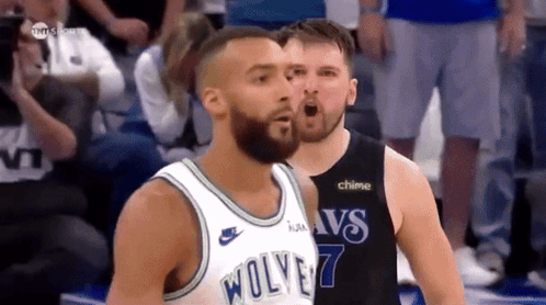A Basketball Player Wearing A Wolves Jersey Stands Next To Another Player GIF