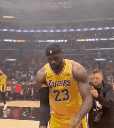 A Basketball Player Wearing A Yellow Lakers Jersey Is Walking On The Court . GIF